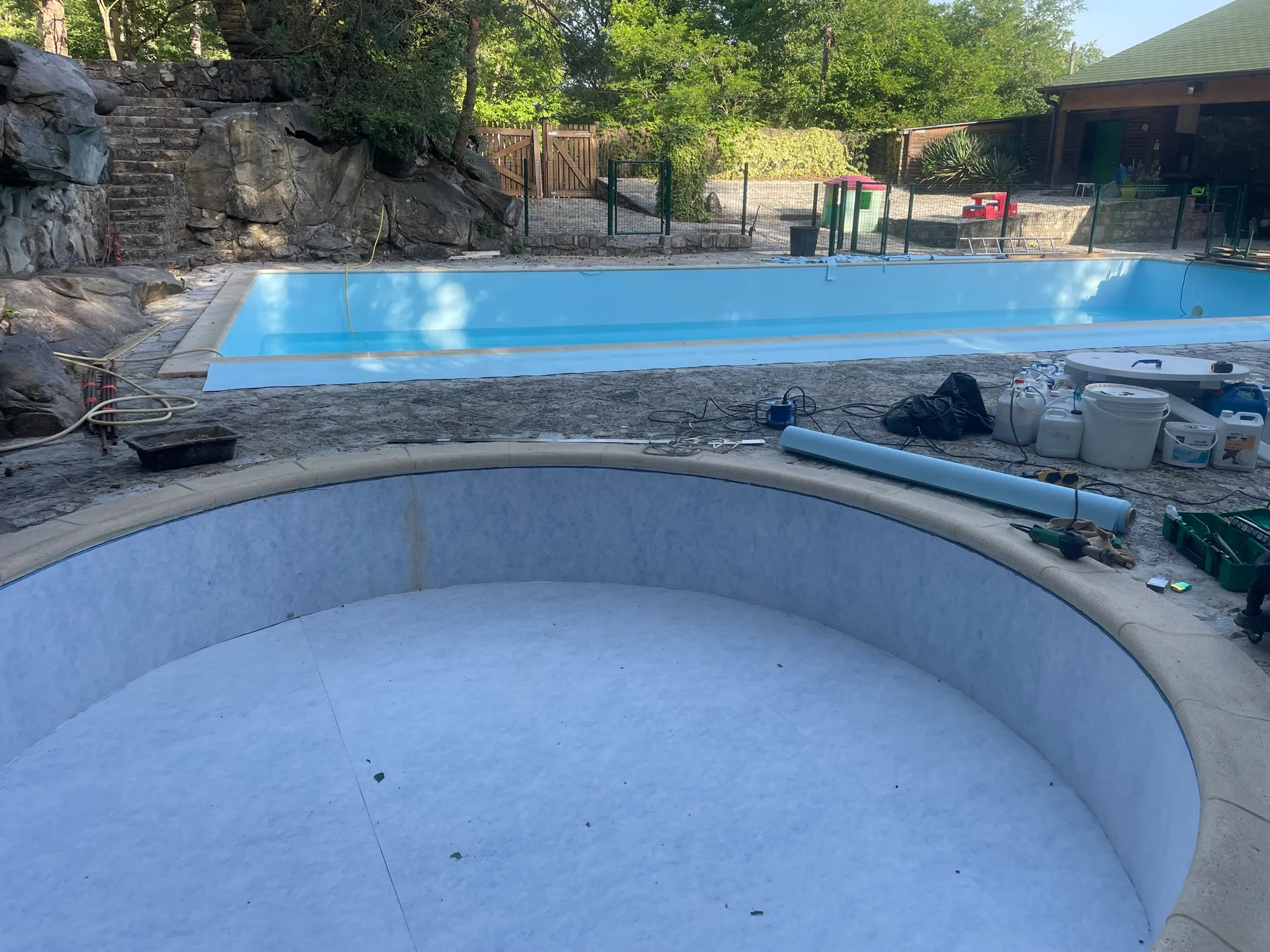 Bassin rond au premier plan, grand bassin en eau derrière, terrasse en pierre