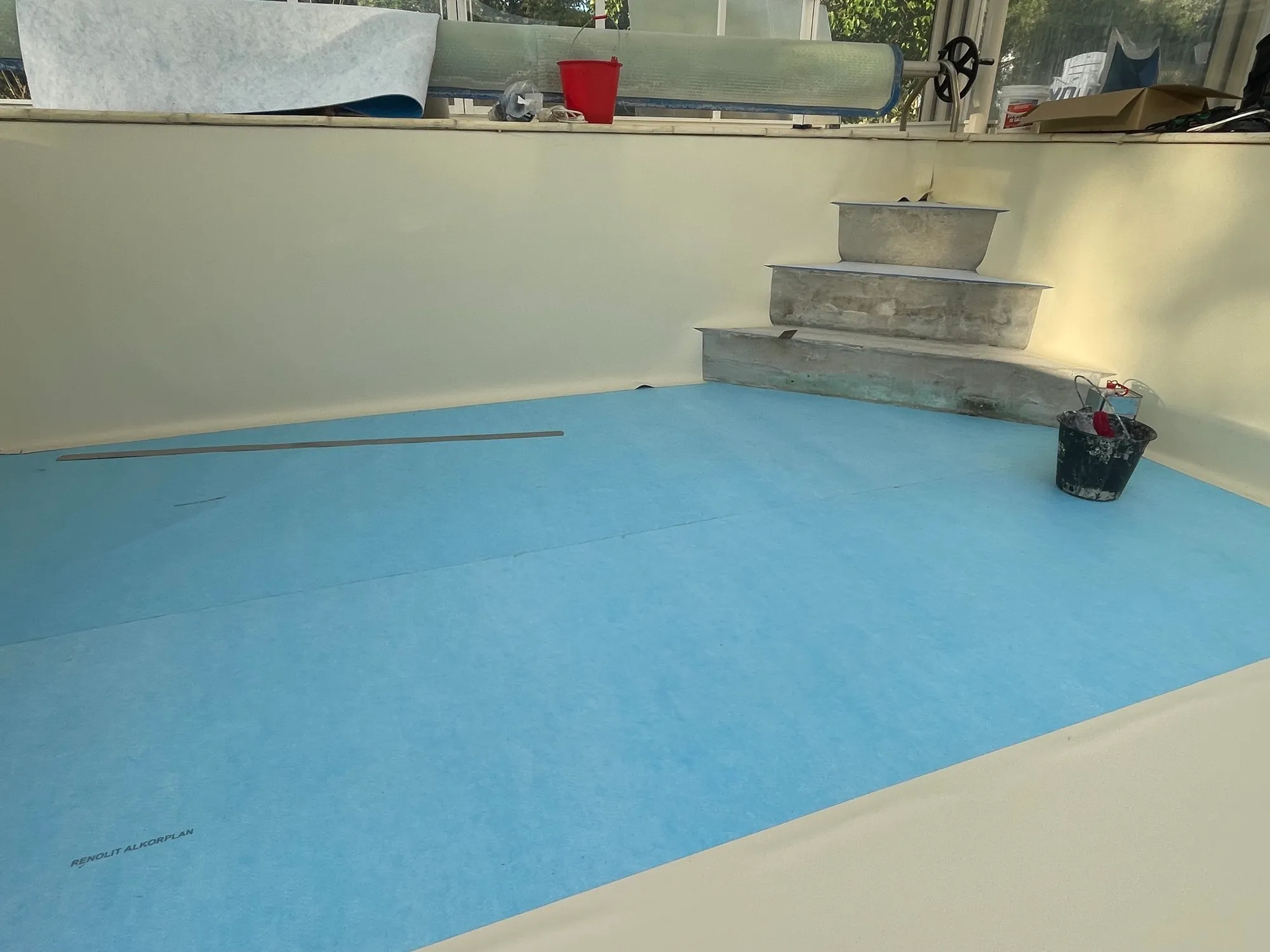 Feutre bleu déroulé sur le fond, parois habillées de liner crème
