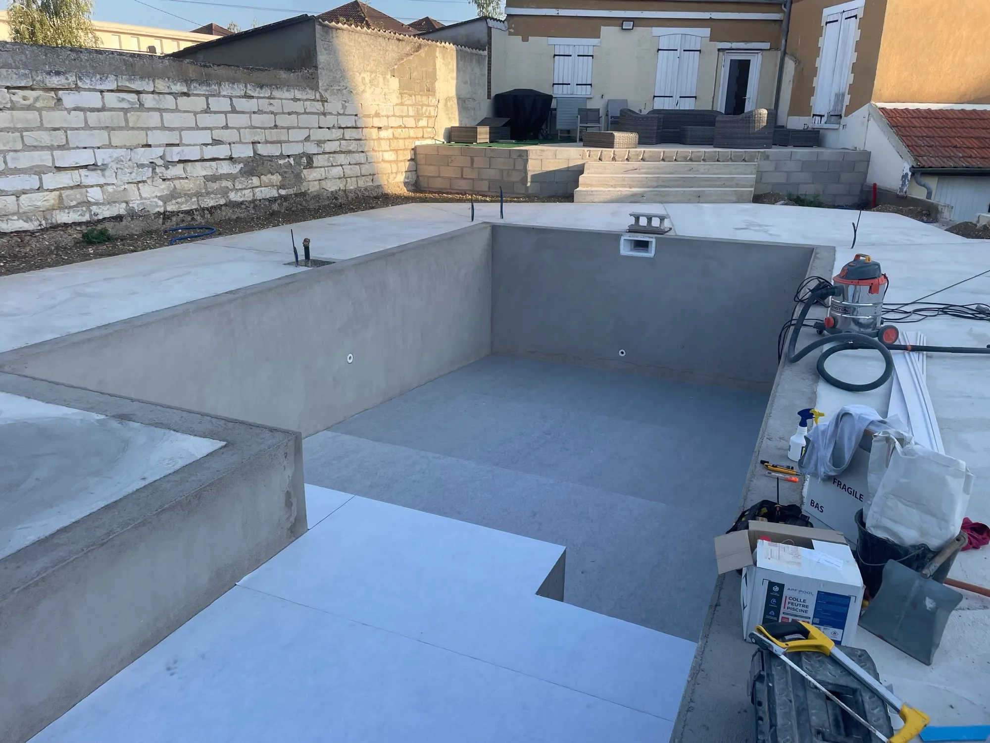Feutre gris collé sur le fond et les marches, parois encore en béton nu