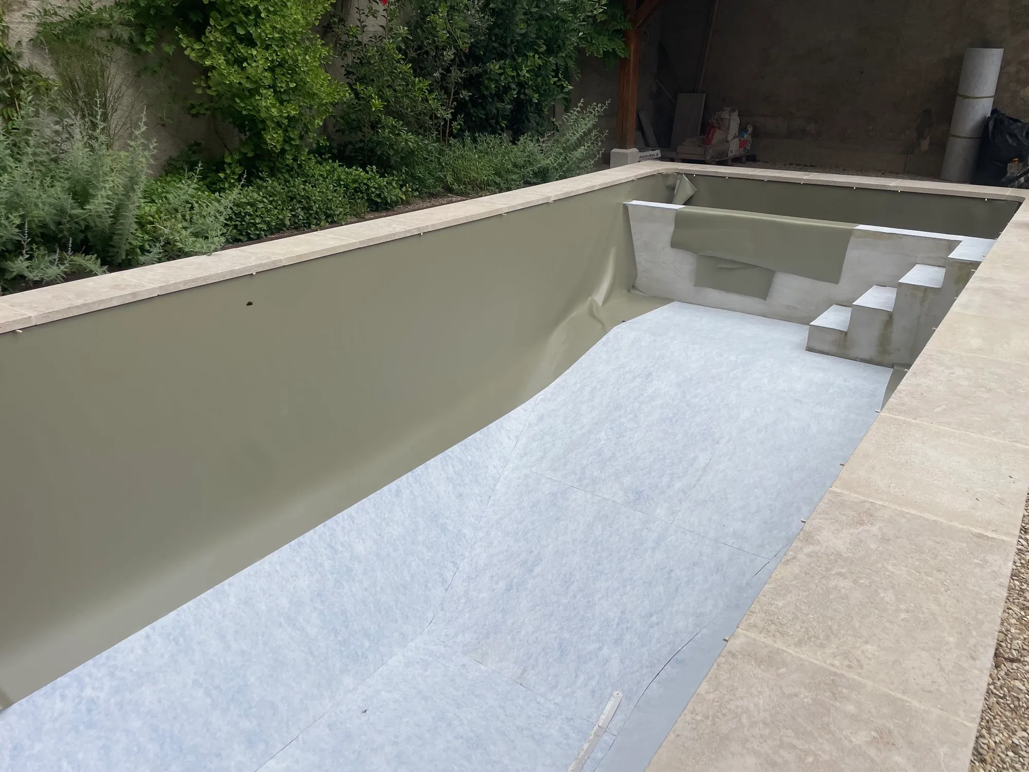 Parois et escalier d’angle habillés de liner kaki, margelles posées
