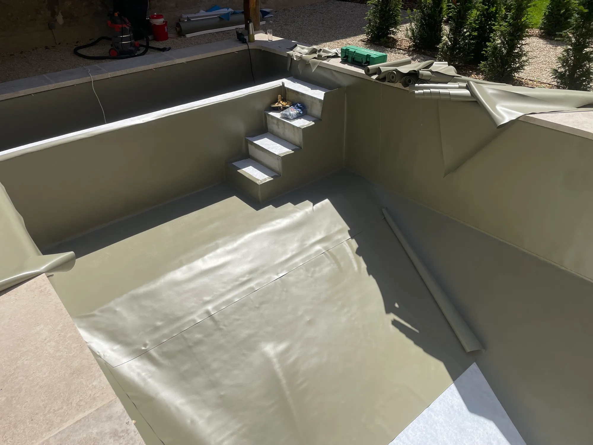 Liner kaki posé sur parois et escalier, lé de fond en cours de pose